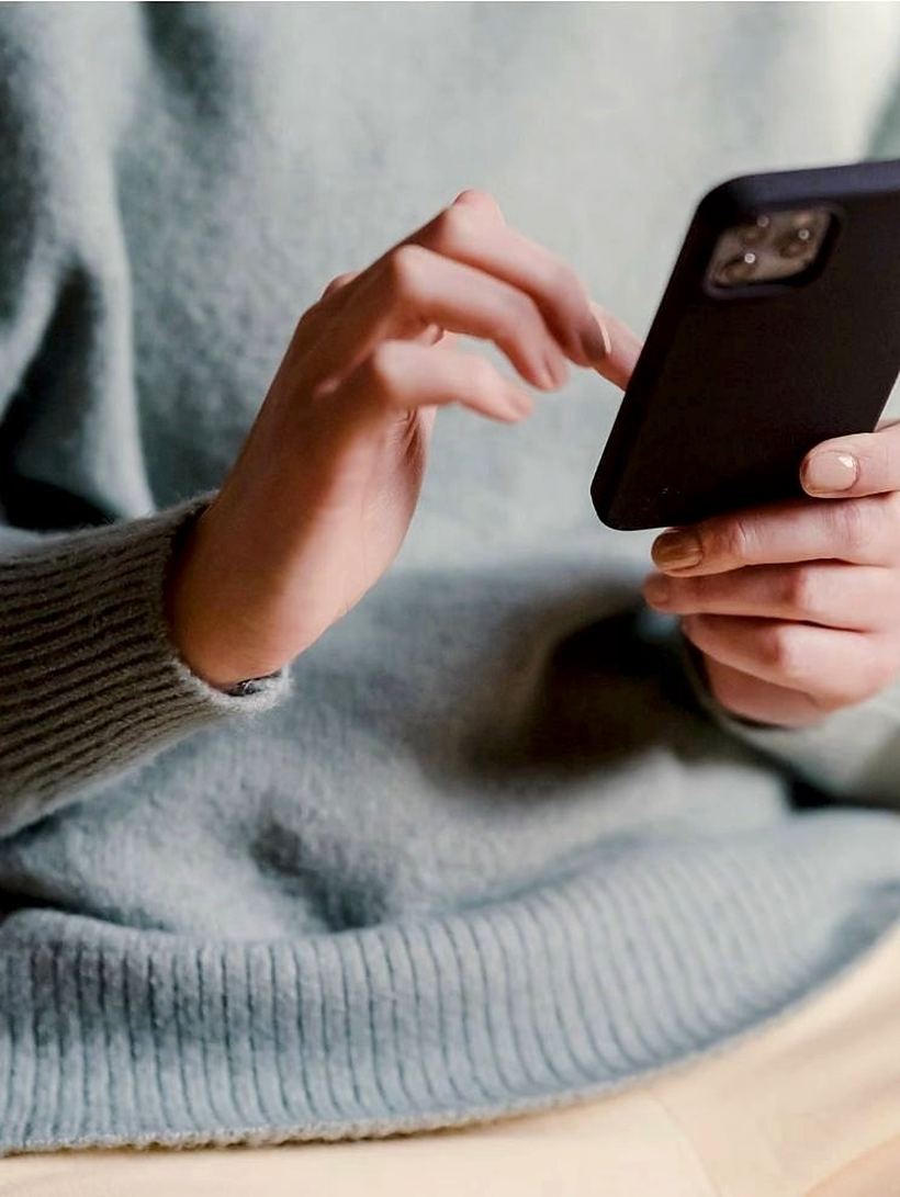 A woman in her fifties looking at her phone in warm daylight.