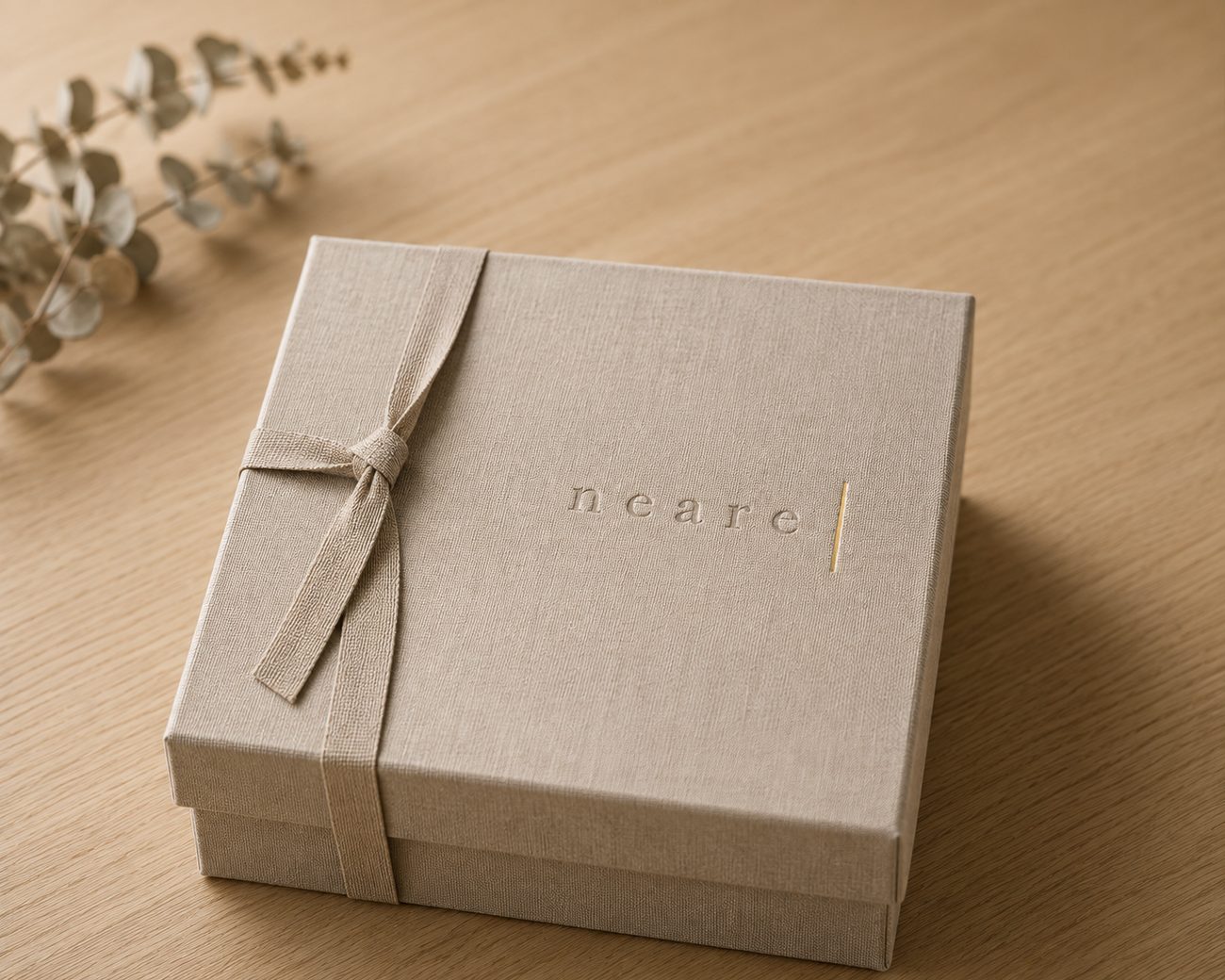The Neare set, wrapped in oat linen and tied with a linen ribbon, resting on a pale oak table beside dried eucalyptus.